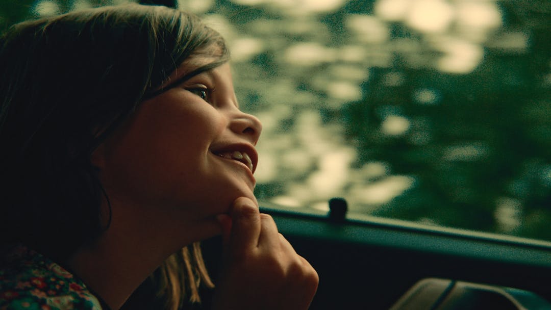 girl looking from window of car smiling