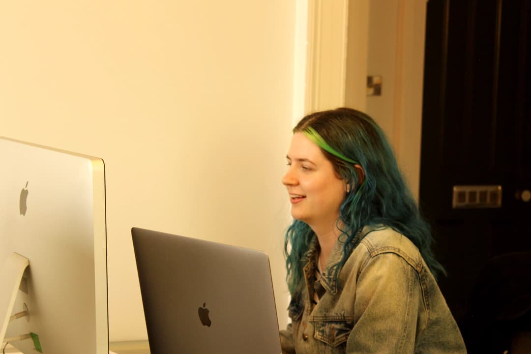 Designer Abi smiling and looking at Apple monitor