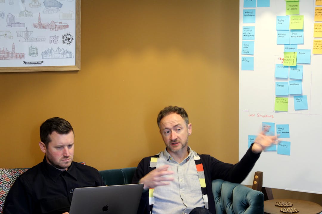 Design Director Lee and Managing Director and co-founder Jim sit next to whiteboard on sofa in Bulb Studios lounge